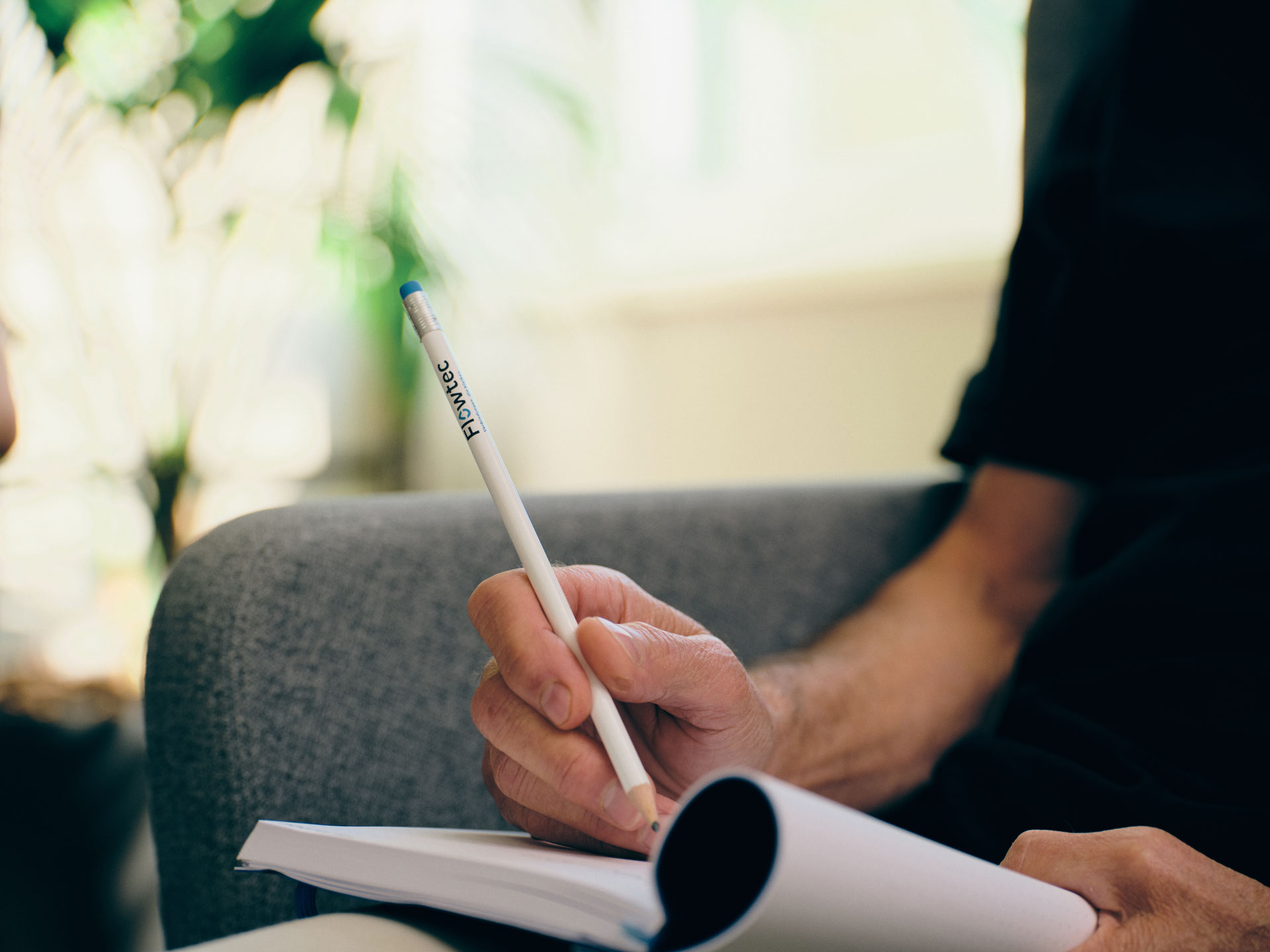 Person macht sich Notizen im Notizbuch während der Arbeit bei Flowtec